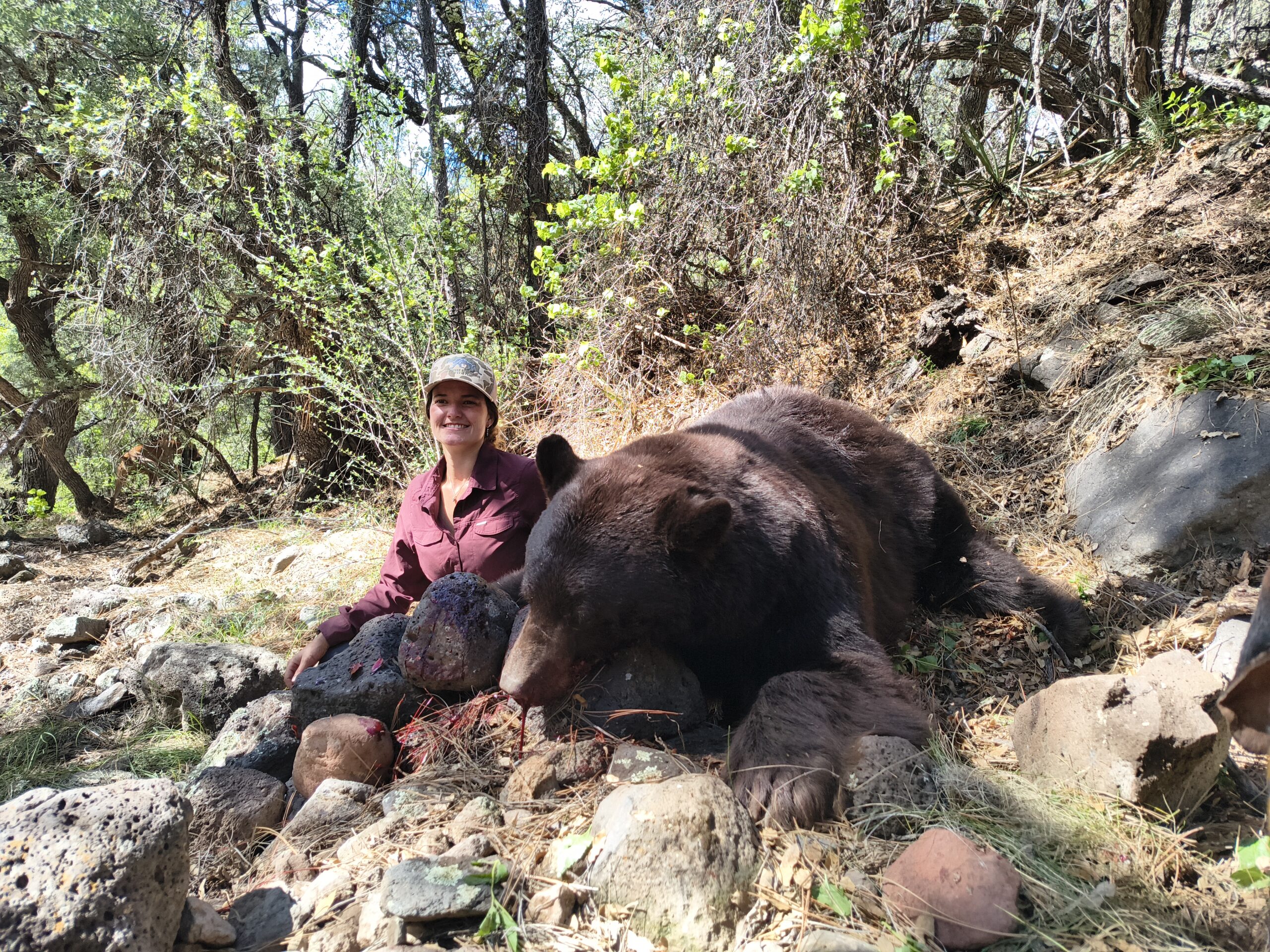 A hunter posing with a black bear that they shot and killed